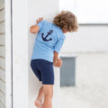 Barn iført Petit Crabe Alex badeshorts i Blue ved stranden.