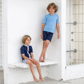 Barn iført Petit Crabe Alex badeshorts i Blue ved stranden.